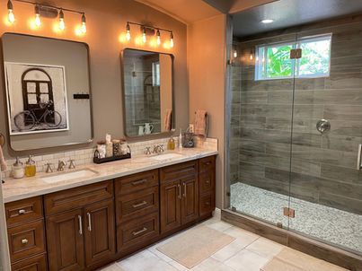 A bathroom with two sinks and a walk in shower.