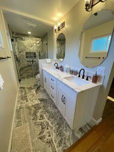 A bathroom with two sinks , a mirror and a walk in shower.
