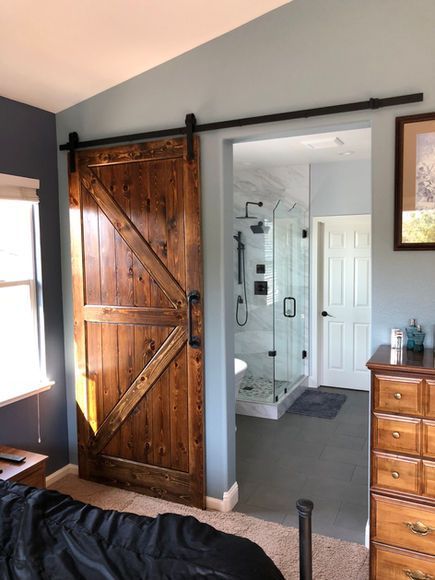 A bedroom with a sliding barn door leading to a bathroom.