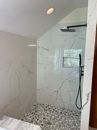 A bathroom with a walk in shower and a window.
