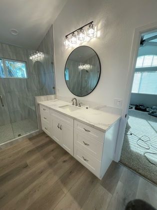 A bathroom with two sinks and a round mirror.