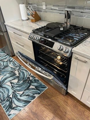 A kitchen with a stove and oven with the door open.