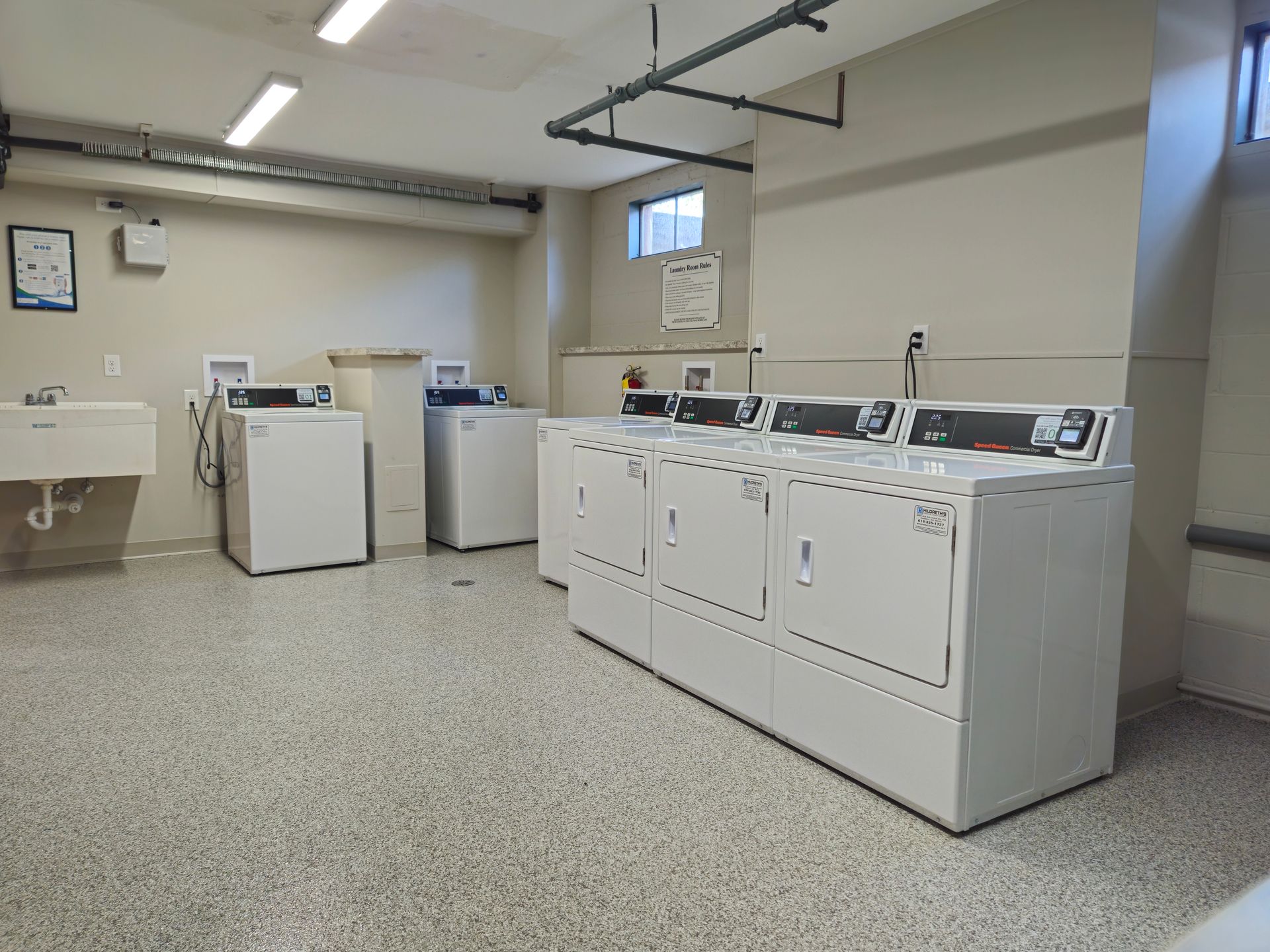 A laundry room with washers and dryers and a sink.