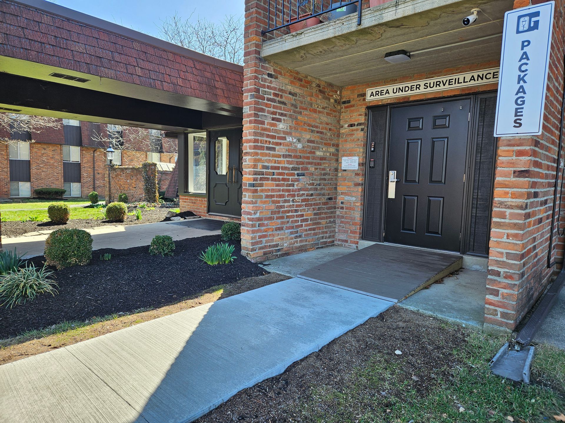 A brick building with a black door and a ramp leading to it.