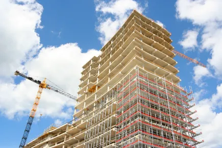 High-rise building under construction with cranes against a blue sky