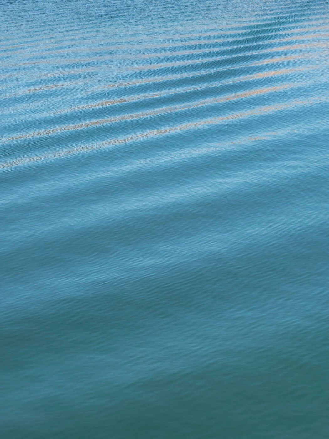 Gentle ripples moving across calm blue water
