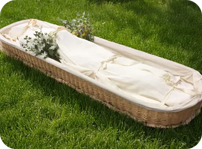 Wicker baby bassinet with white bedding and floral greenery on grass
