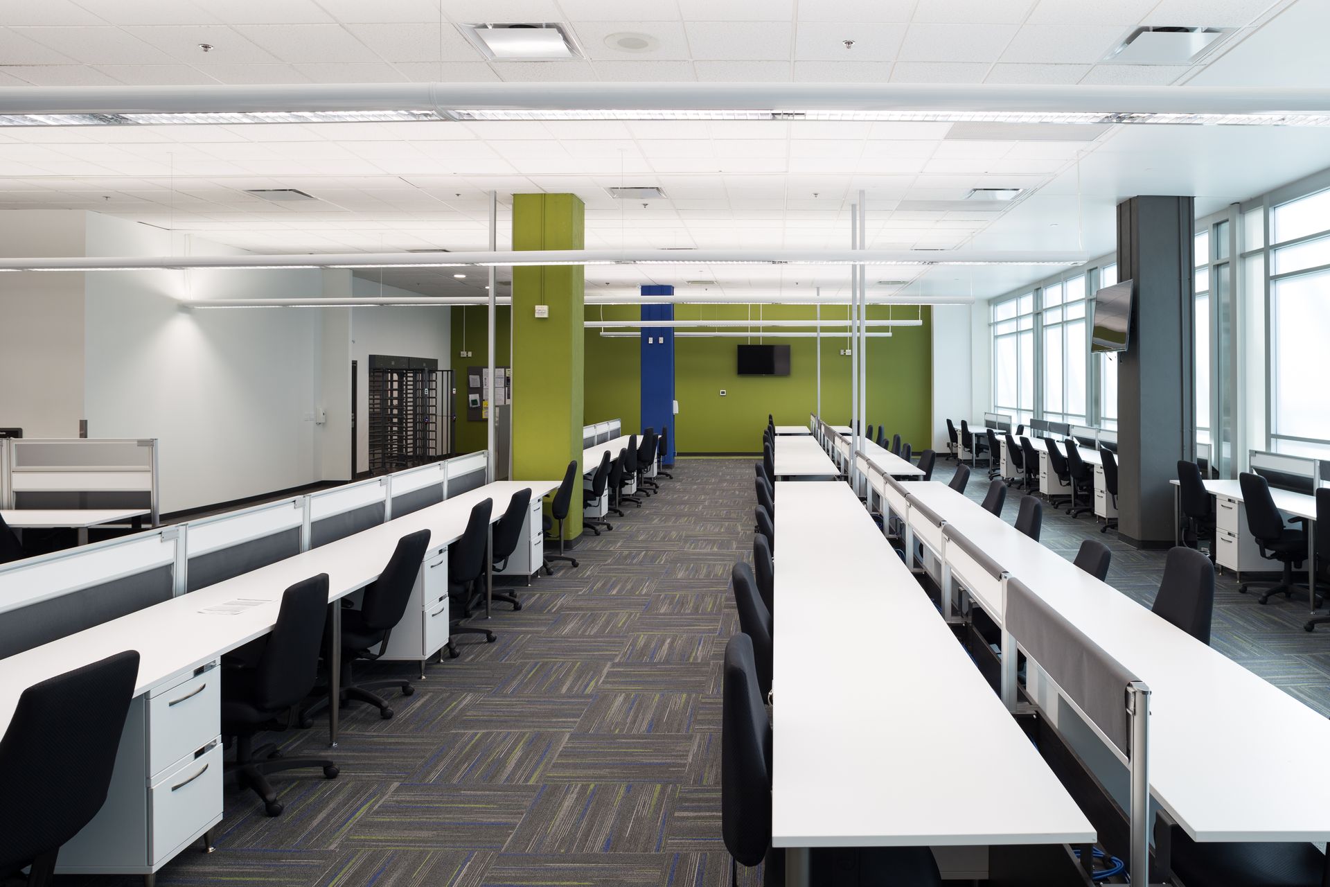 Long, open office space with rows of desks, chairs, and colorful columns.