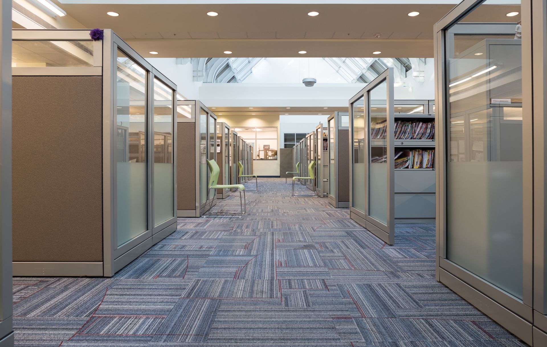 Library hallway with individual study carrels, glass walls, and patterned carpet.