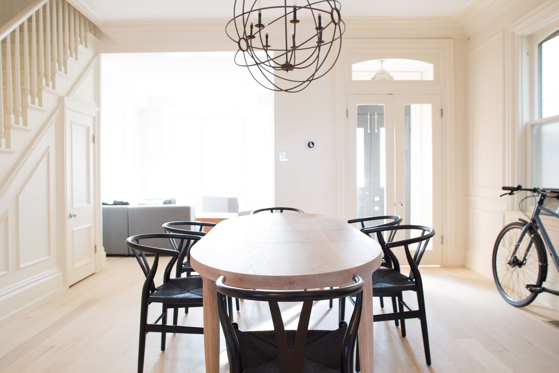 Bright dining room with wooden table, black chairs, and a bicycle near a window.