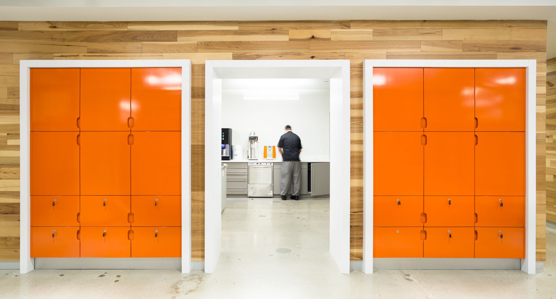 Three orange storage cabinets flanking a doorway. A person stands in the doorway. Wood paneling behind the cabinets.