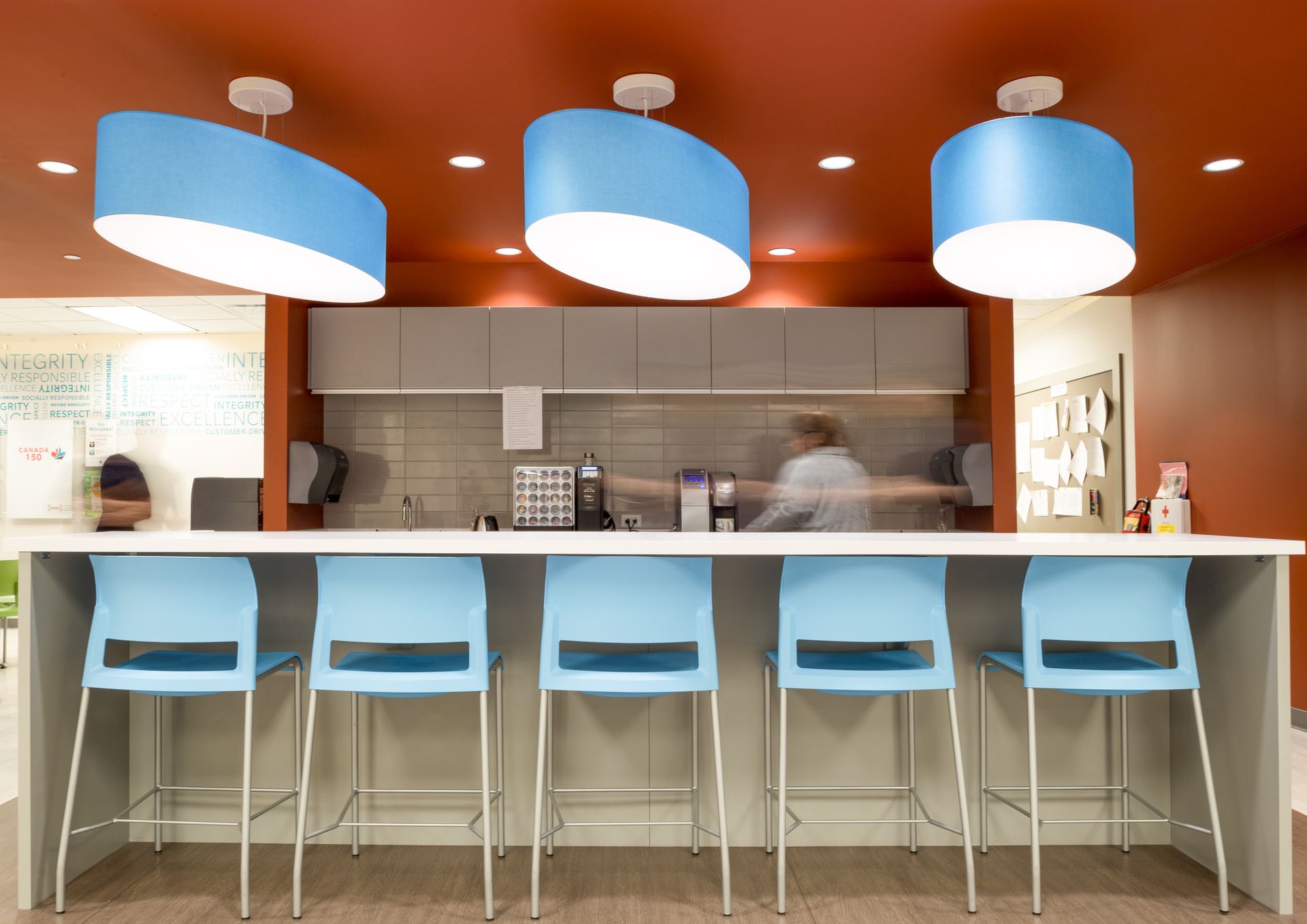 Bar with blue chairs and light fixtures under an orange ceiling.
