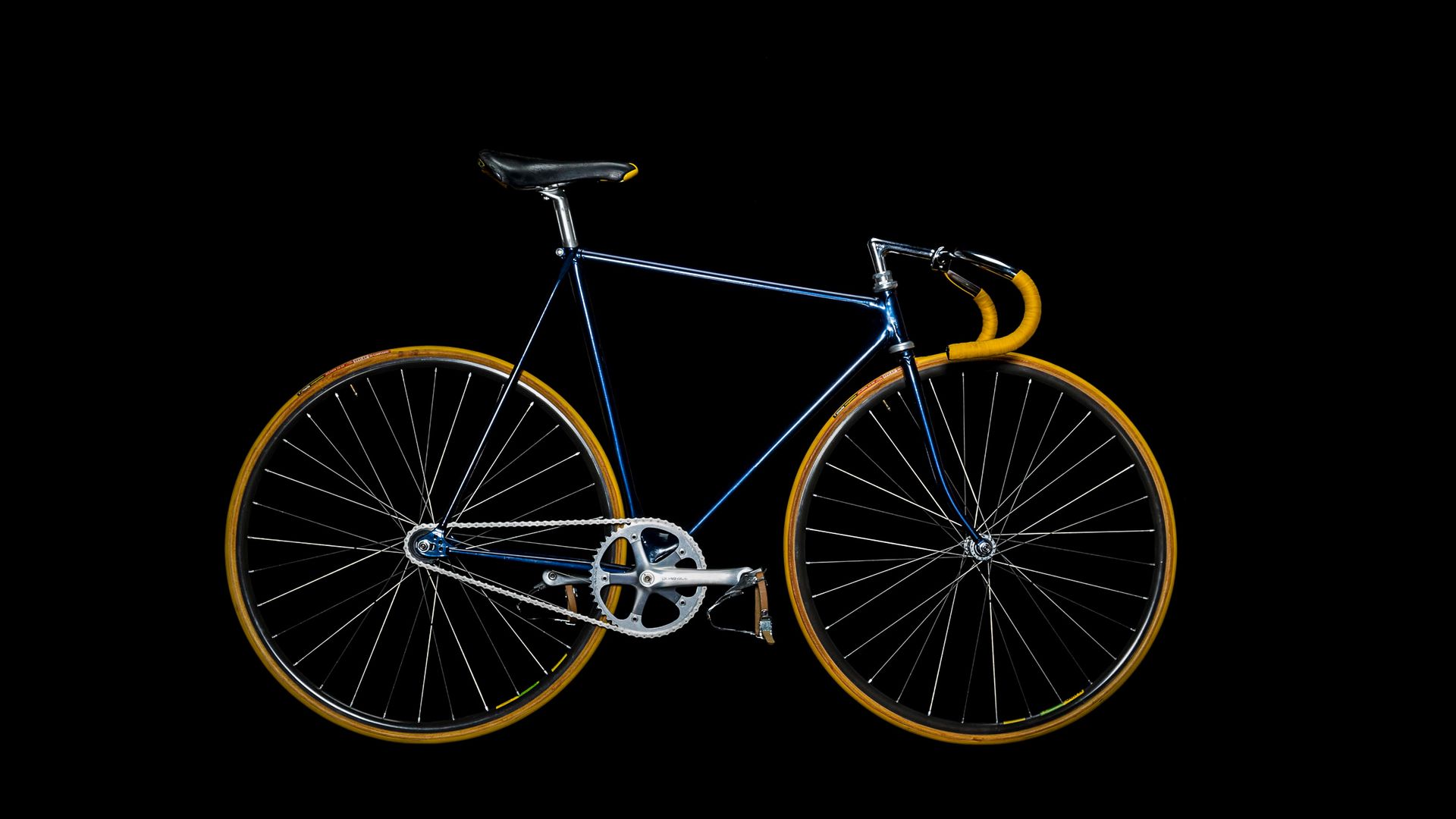 Blue road bicycle with yellow handlebars and wheels against black background.