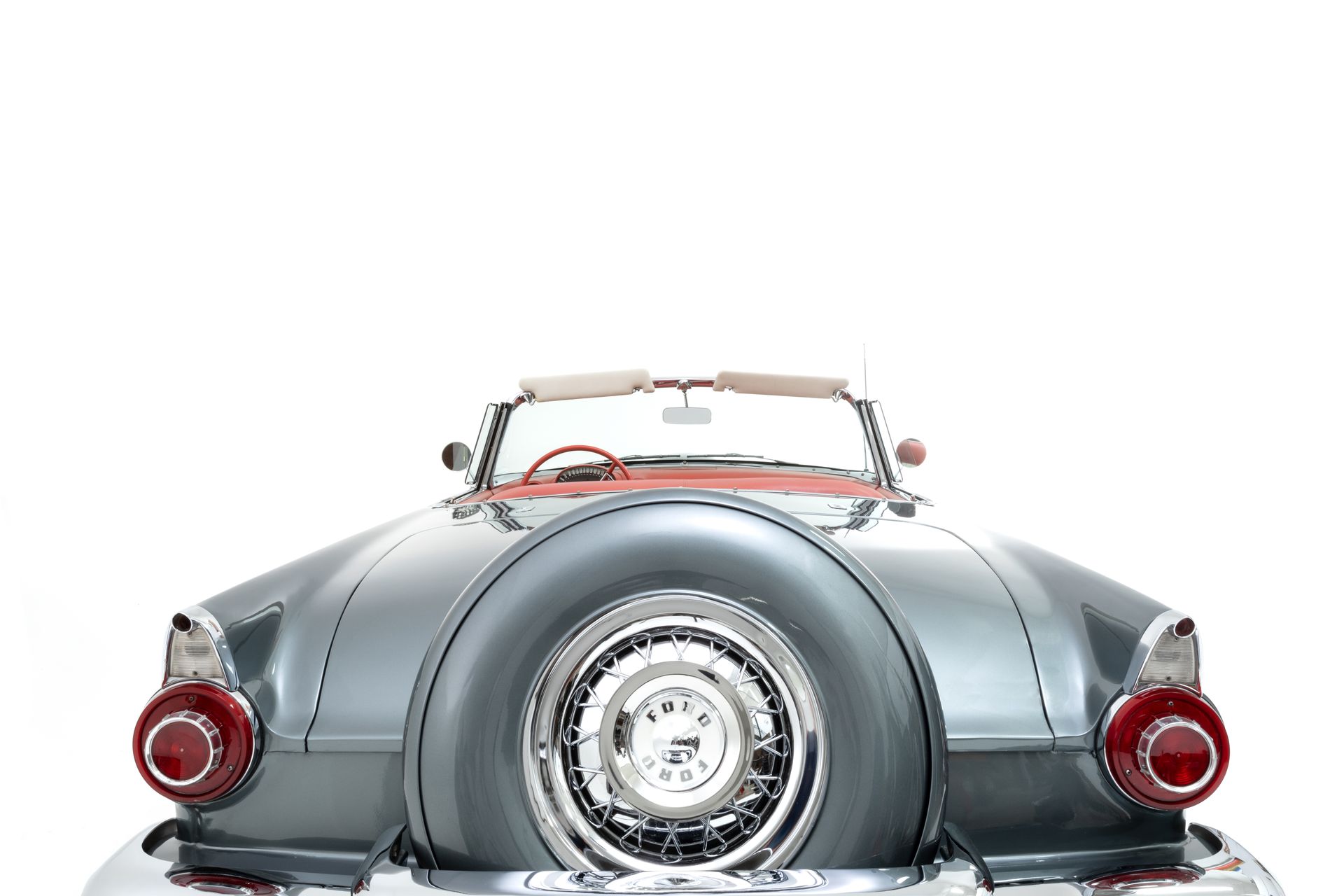 Classic blue convertible car with red interior, spare tire, and round taillights.