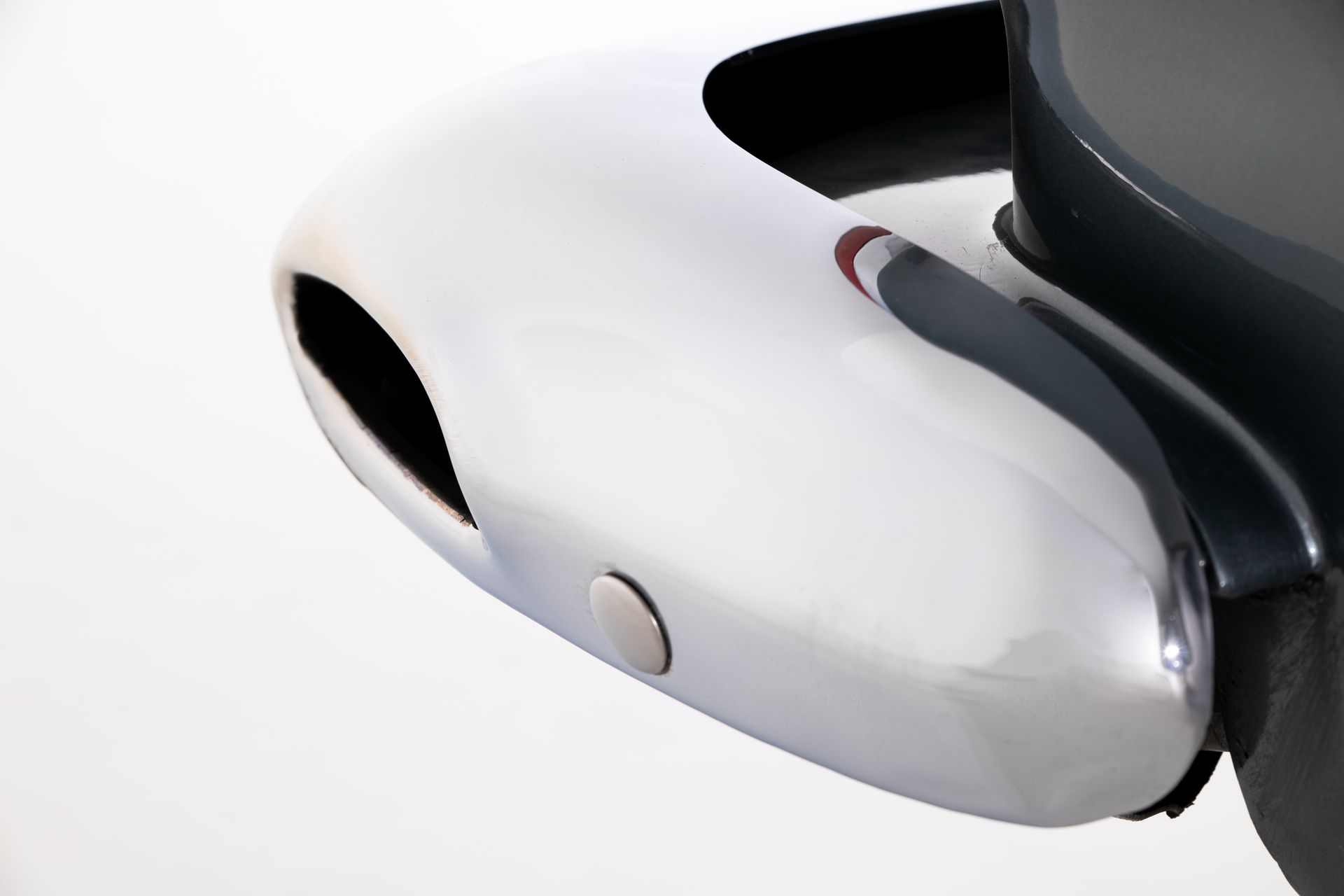Chrome bumper on a dark vehicle, reflecting light, with a small button.