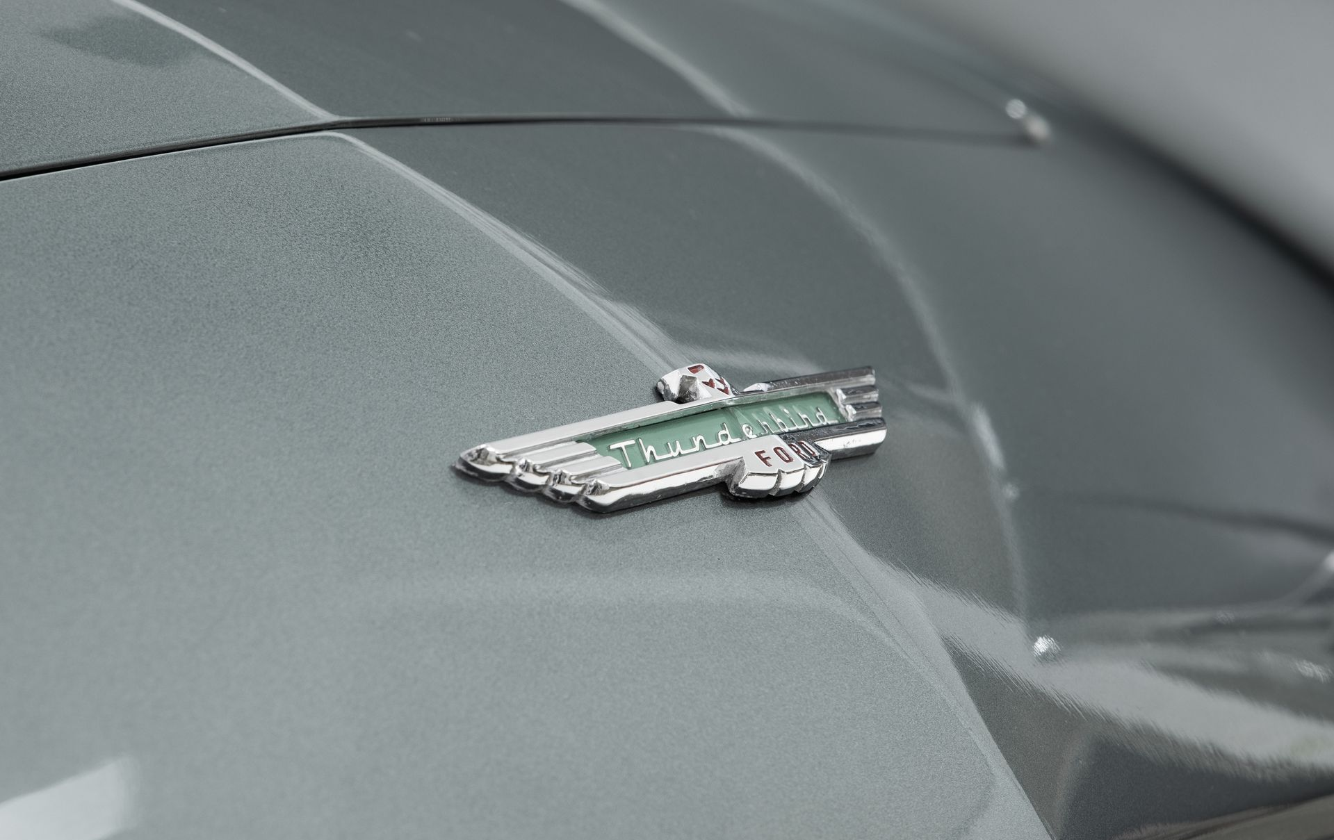 Aston Martin emblem on a grey car hood.