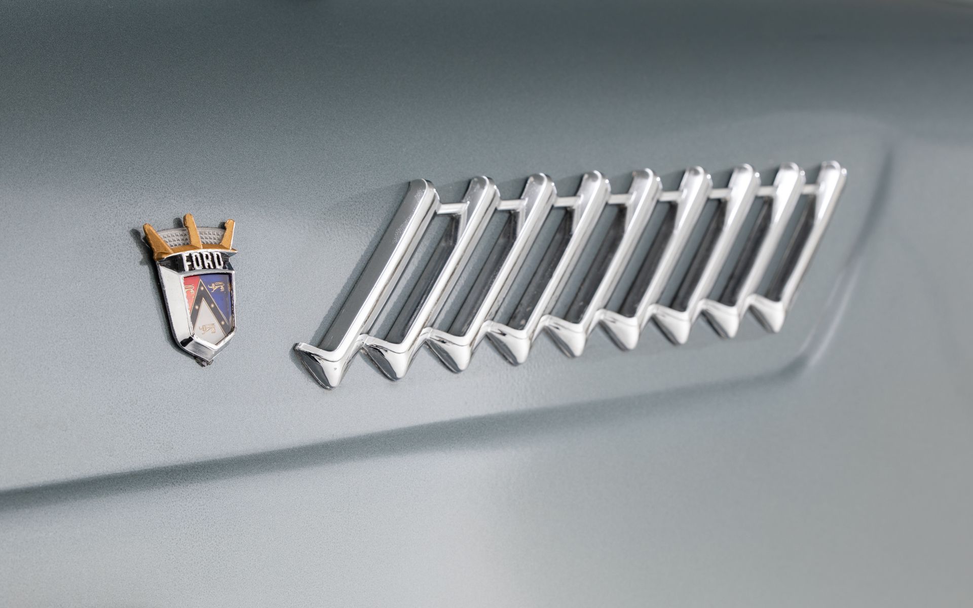 Silver car dashboard with emblem and angled air vent.