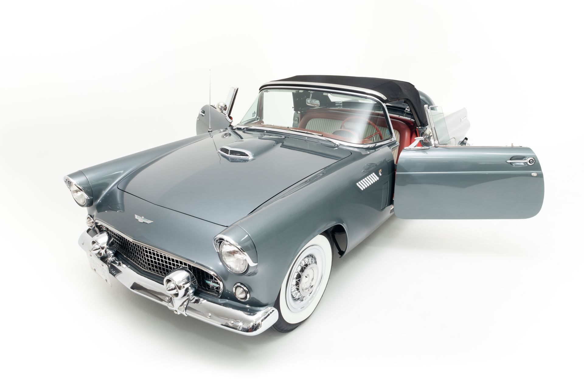 Gray vintage convertible with open doors, white-walled tires, and a black convertible top on a white background.