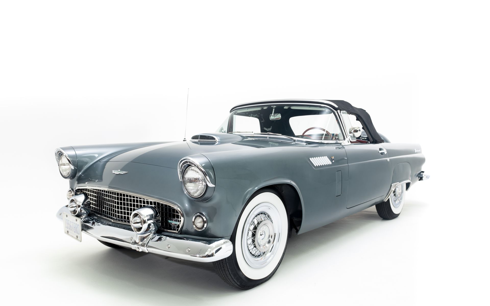Gray 1957 Ford Thunderbird convertible with white-wall tires, chrome accents, and black convertible top.