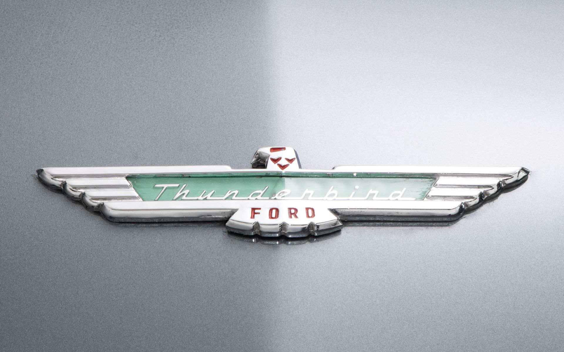 Ford Thunderbird emblem on a gray car surface, featuring a winged logo with 