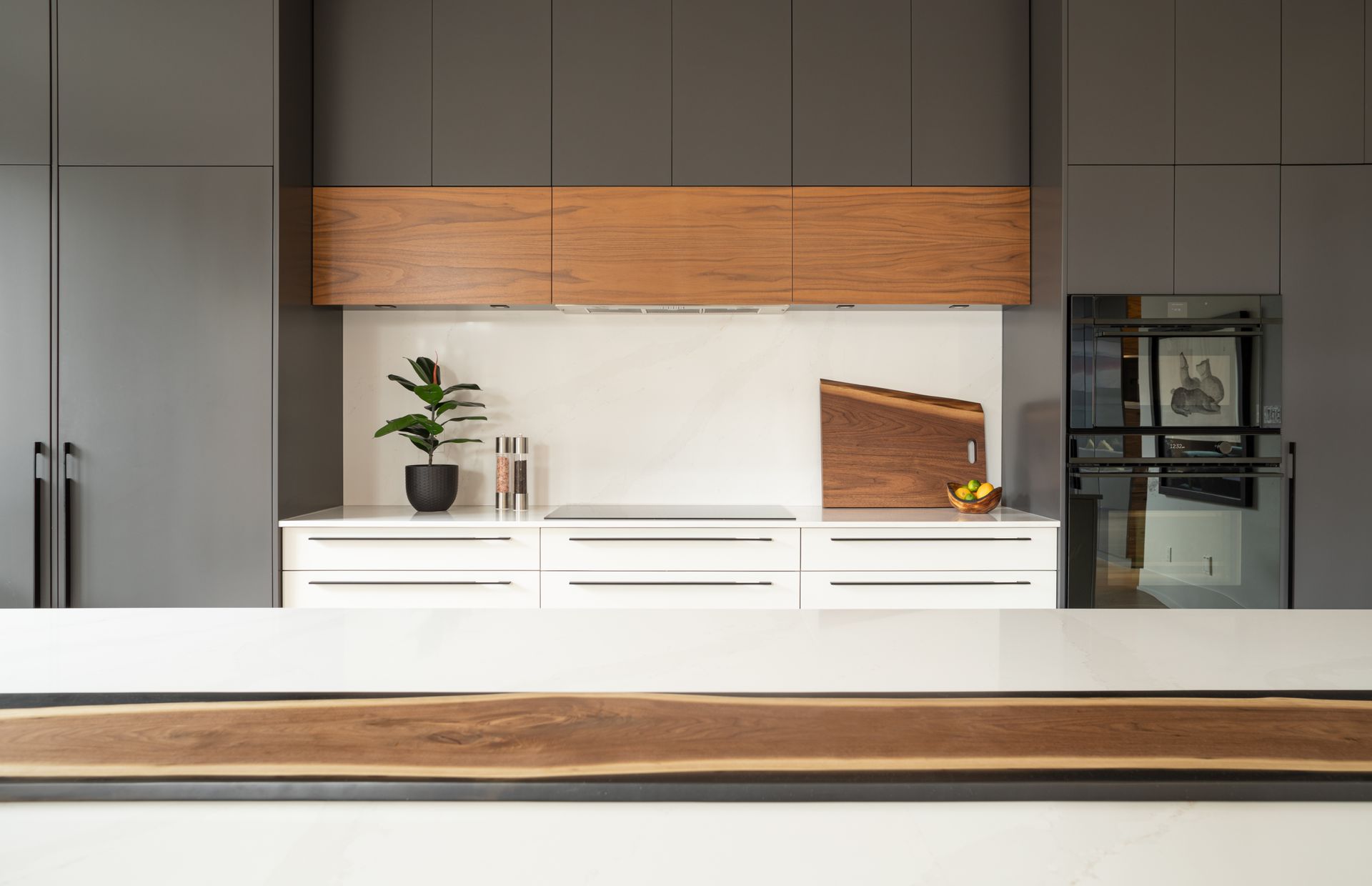 Modern kitchen with gray cabinets, white countertops, and wooden accents.