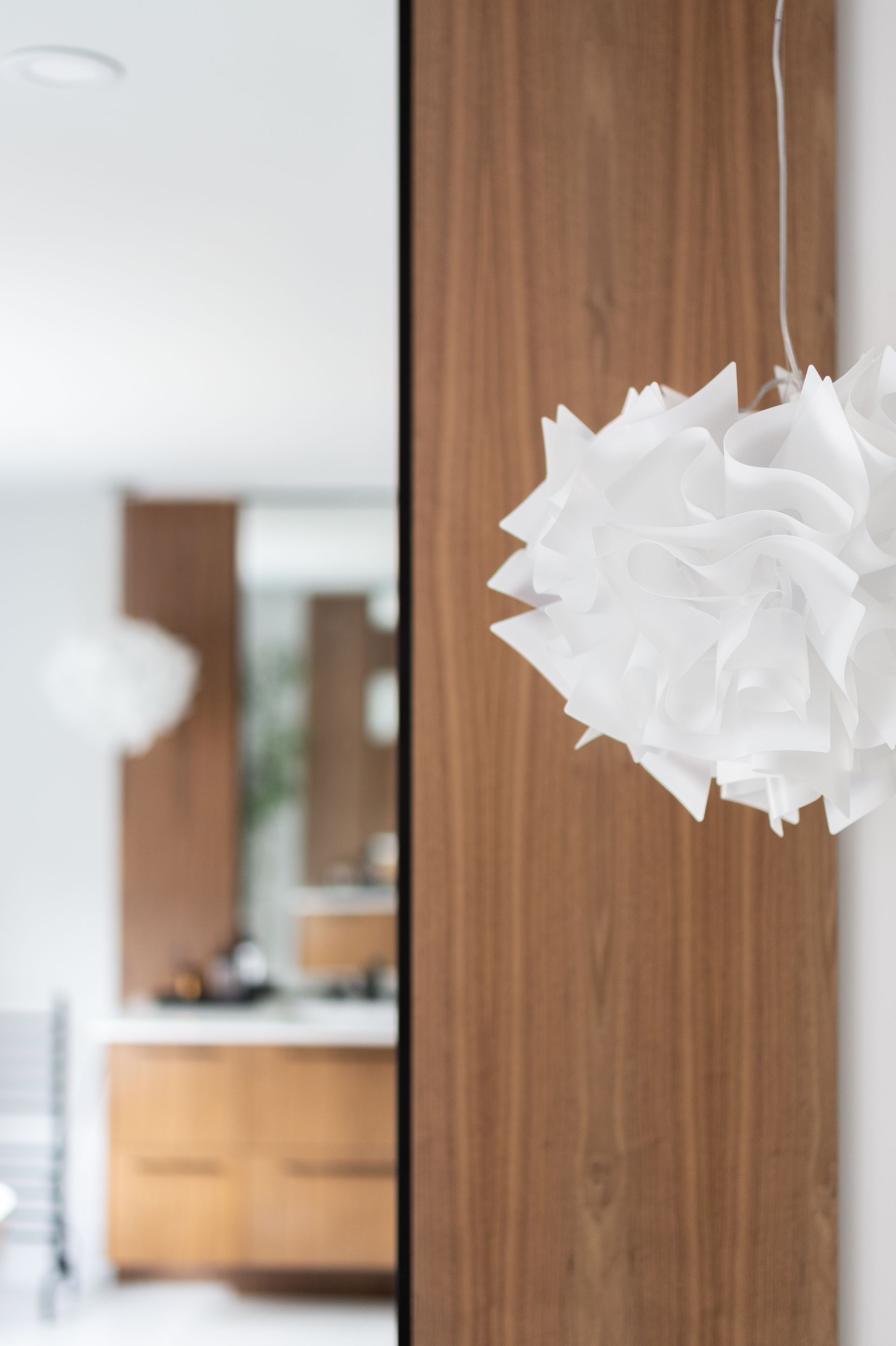 White paper pendant lamp in a room with wood paneling.
