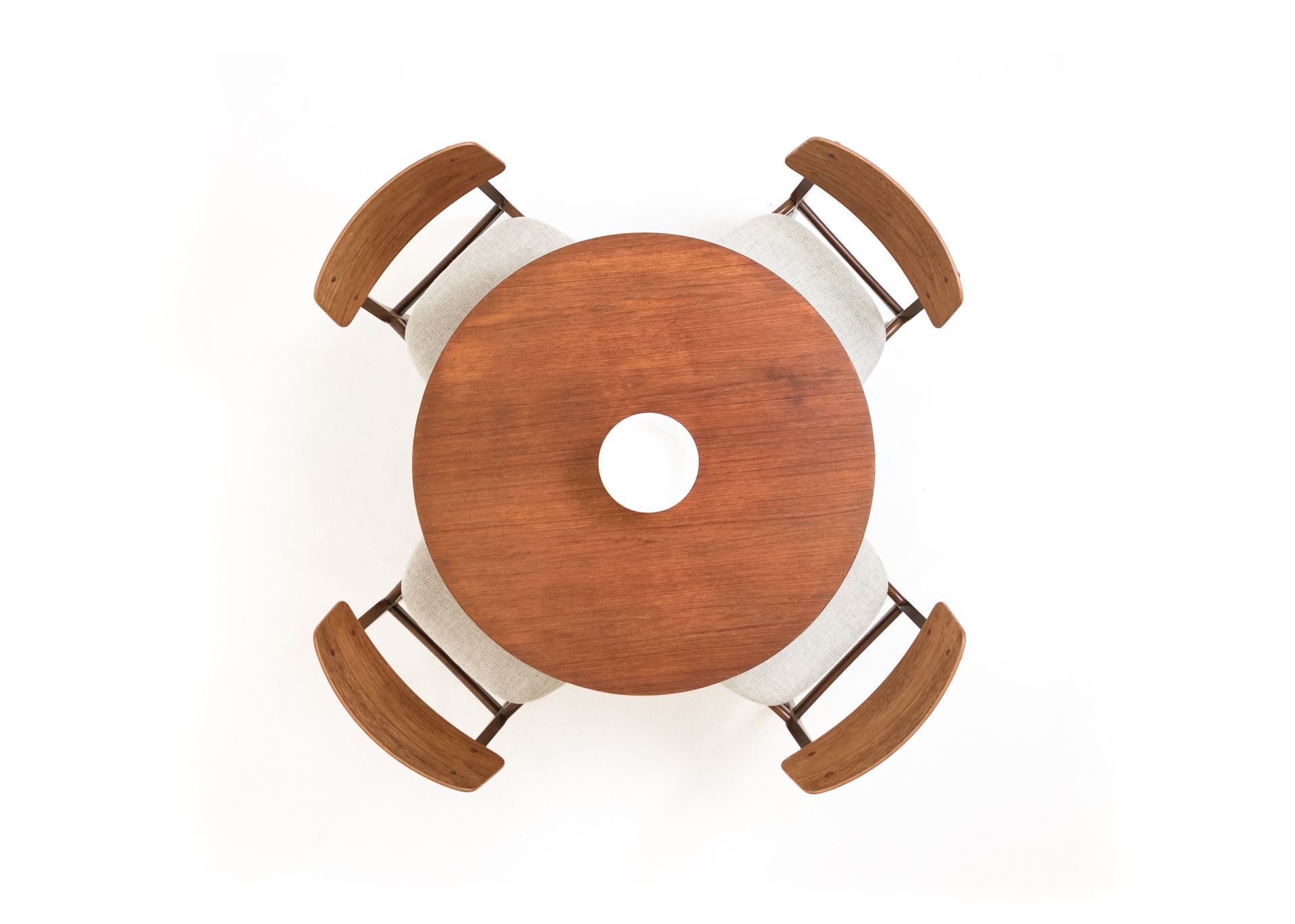 Overhead view of a round wooden table with a white hole in the center, surrounded by four chairs.