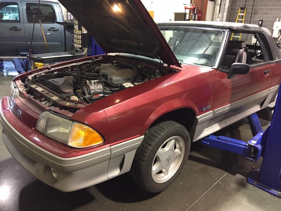 a red car with the hood up is on a lift