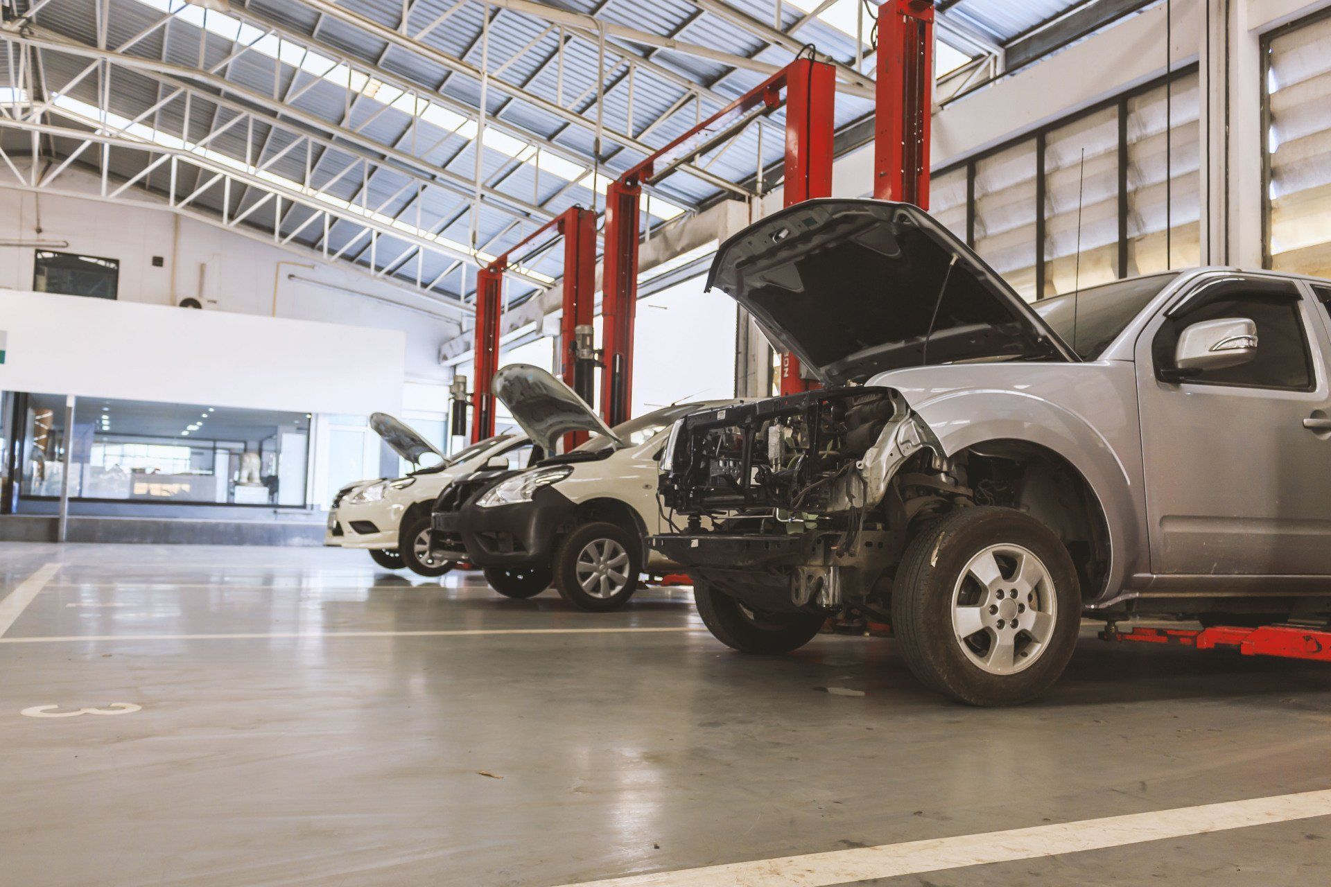 a row of cars are parked in a garage with their hoods open .