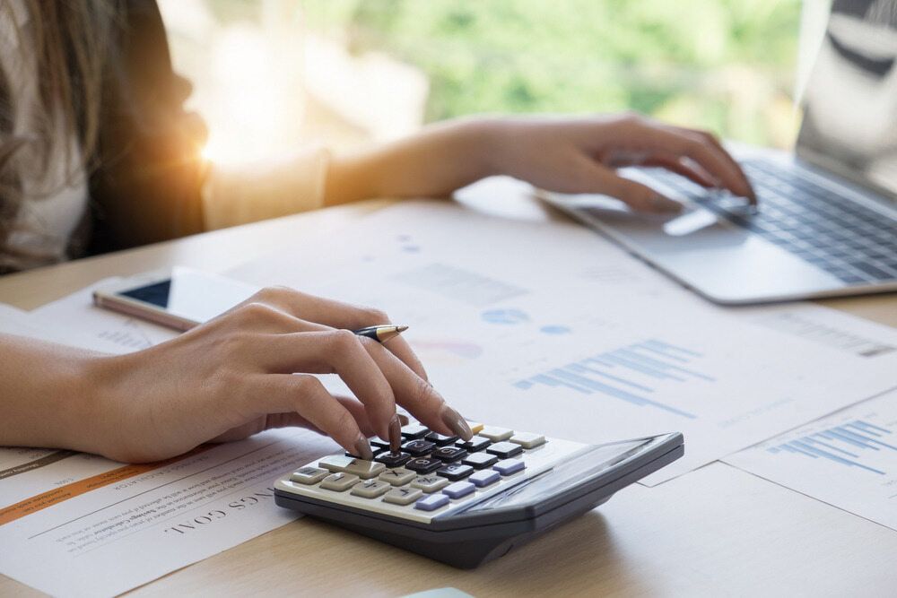 Person Using a Calculator and Laptop at A Desk, Reviewing Financial Documents — SDM Accounting & Taxation Services In Cooroy, QLD