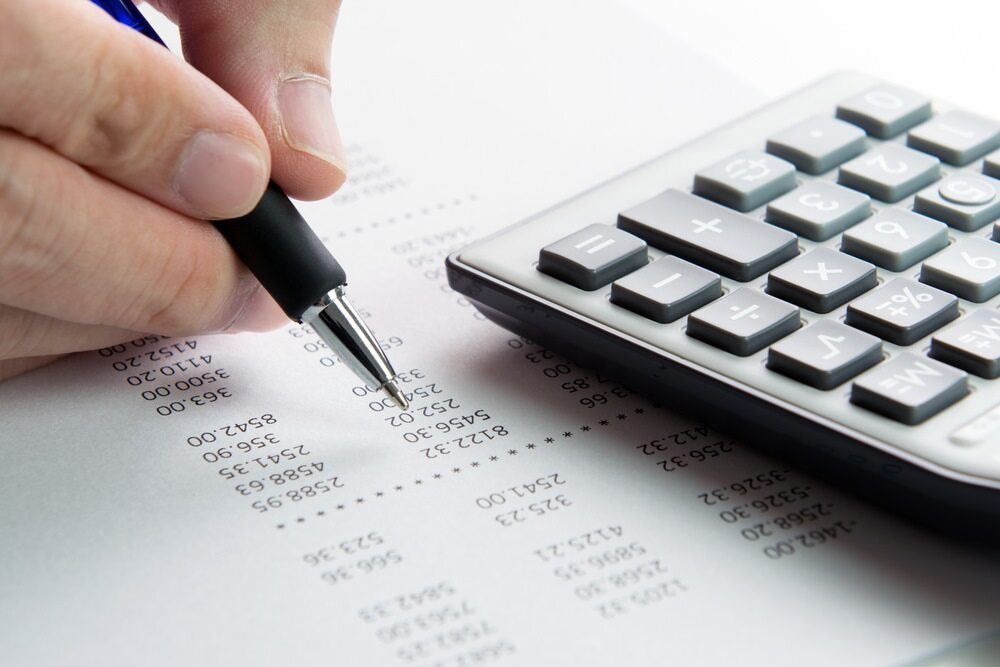 Person Using a Pen to Review Financial Documents Next to A Calculator — SDM Accounting & Taxation Services In Cooroy, QLD