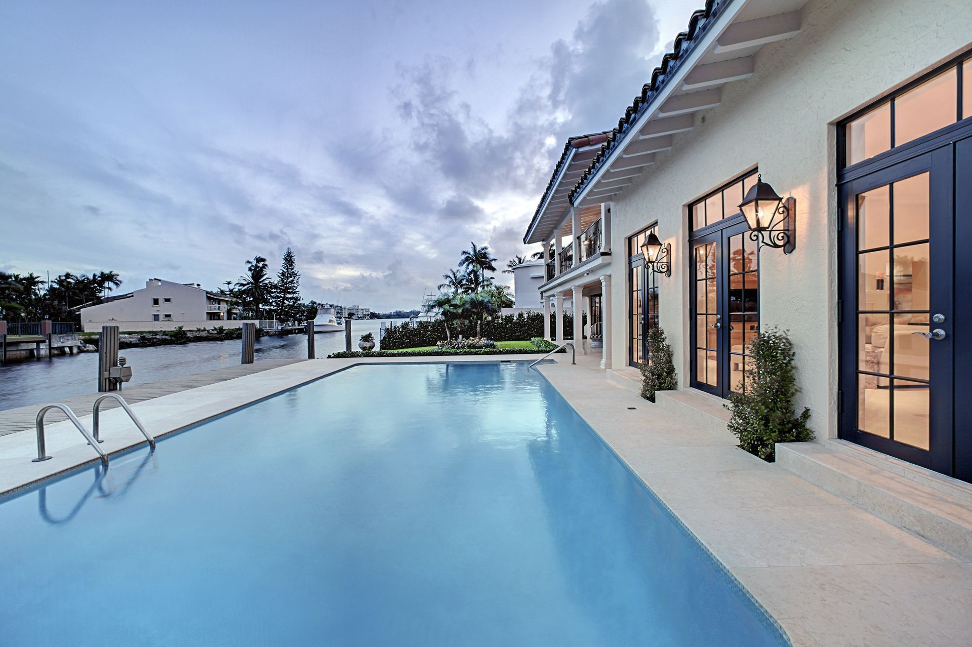 Modern home exterior with a long blue swimming pool at dusk
