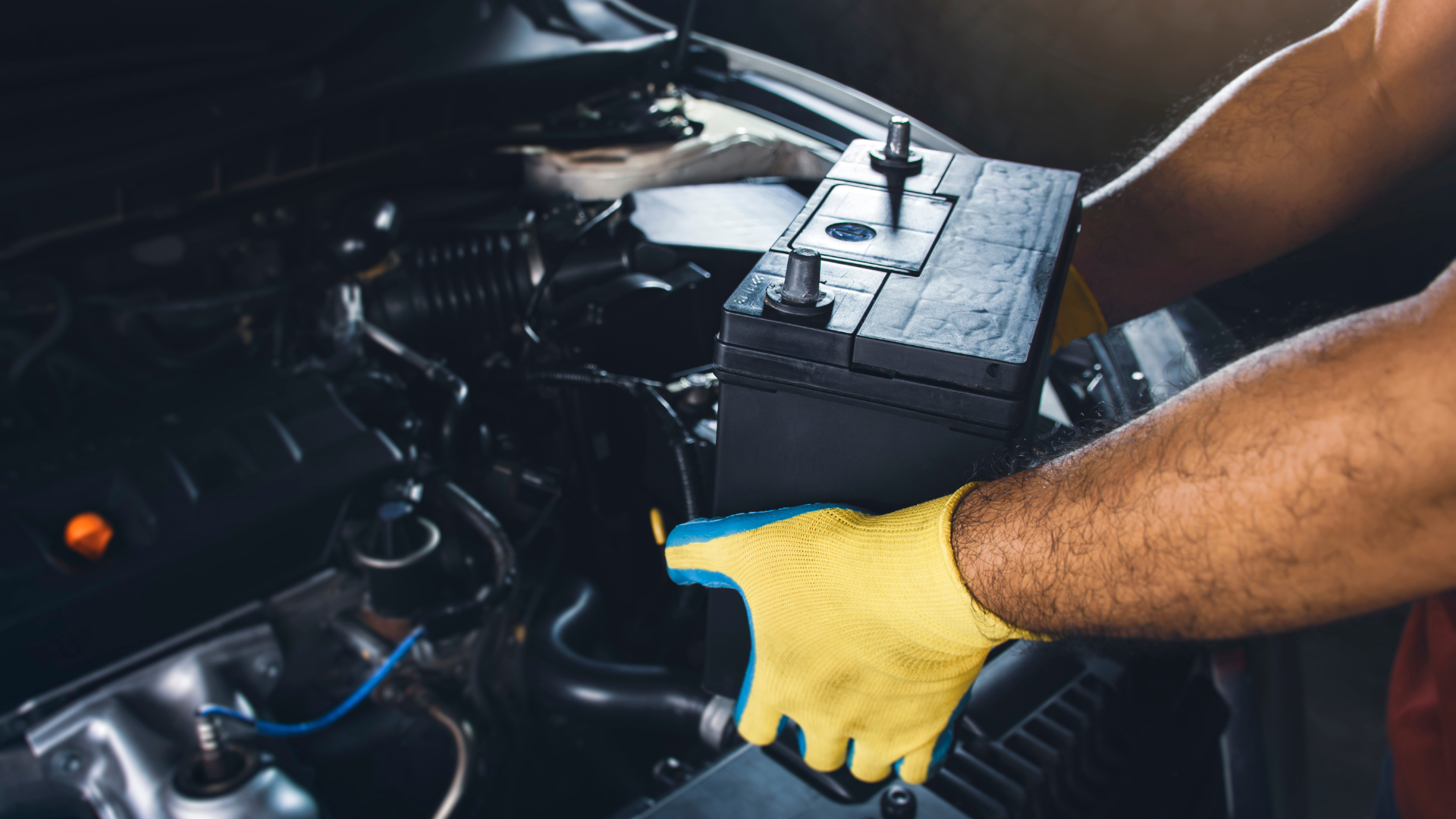 A mechanic is working on a car engine with a wrench.