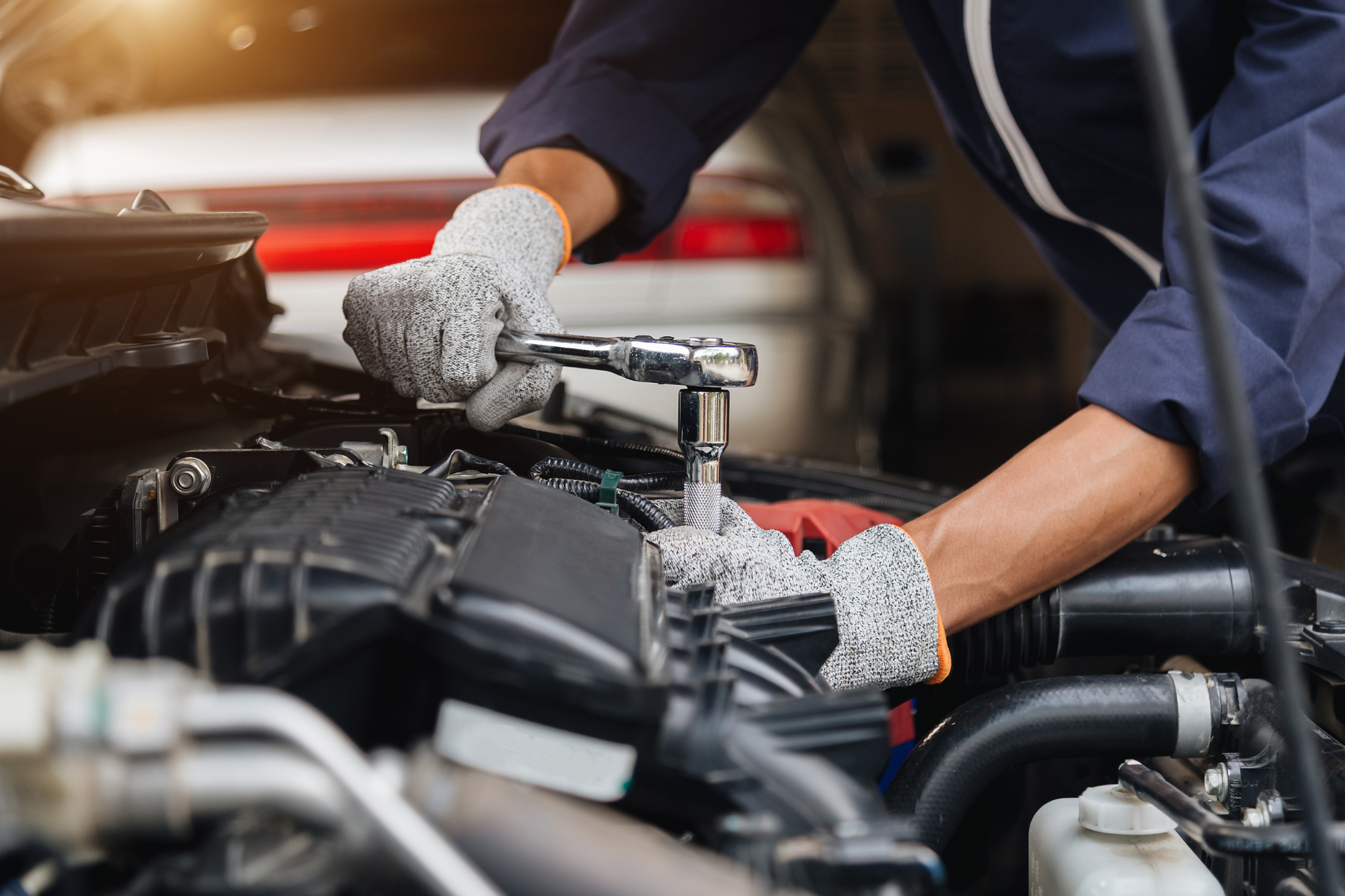 A mechanic is working on a car engine with a wrench.