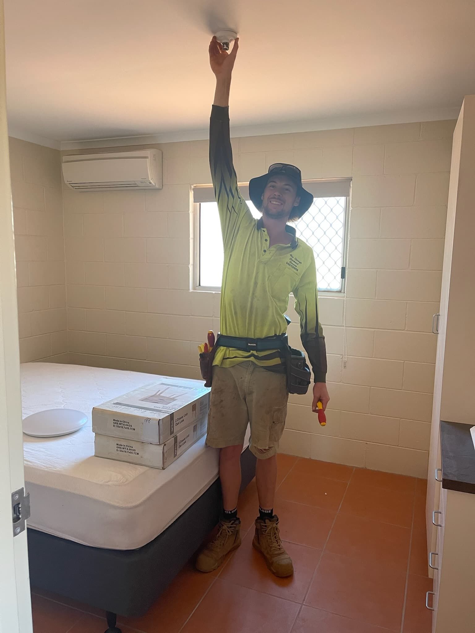 A Person Is Installing A Smoke Detector On The Ceiling — Alice Springs Electrical Services In Araluen, NT