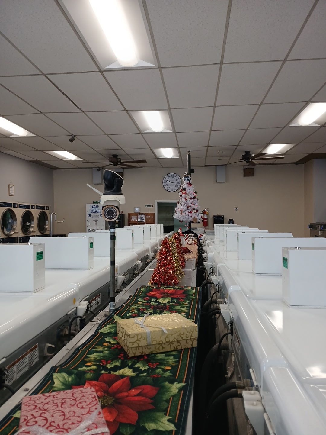 A row of laundromat washers decorated with festive Christmas ribbons, garland, and gift boxes.