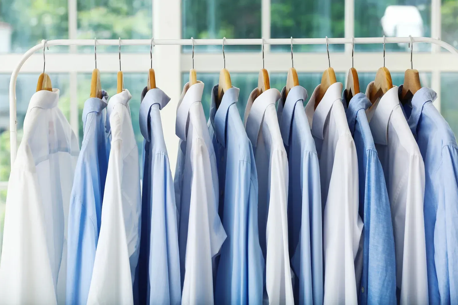 A row of blue and white shirts hanging on a rack.