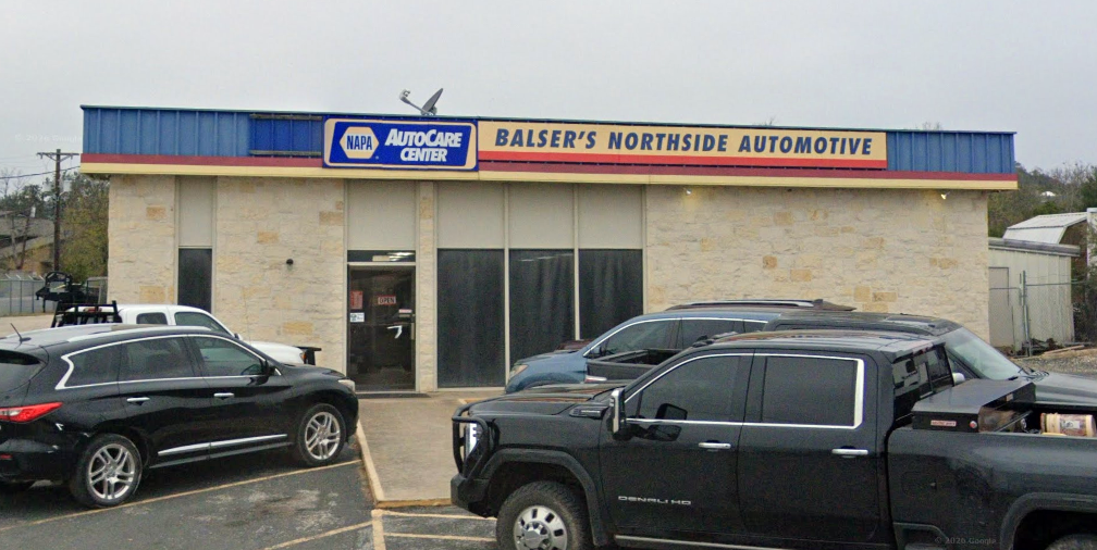 Front view of a used car dealership with parked SUVs and a blue-and-white sign.