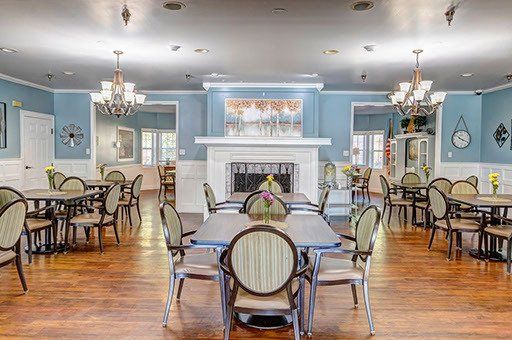 A large dining room with tables and chairs and a fireplace.