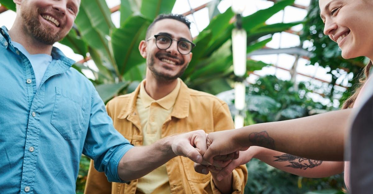 A group of people are putting their hands together in a greenhouse.
