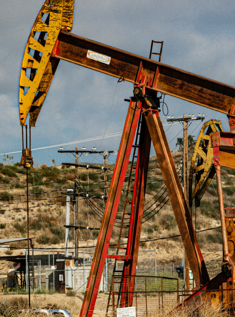 Oil pumpjacks in a desert landscape under a blue sky.