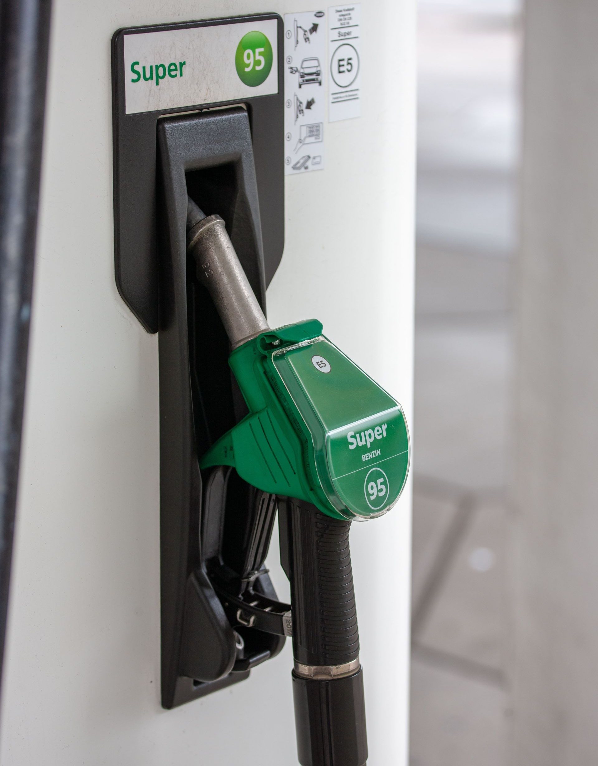 Green fuel nozzle inserted into a gas pump labeled “Super 95”