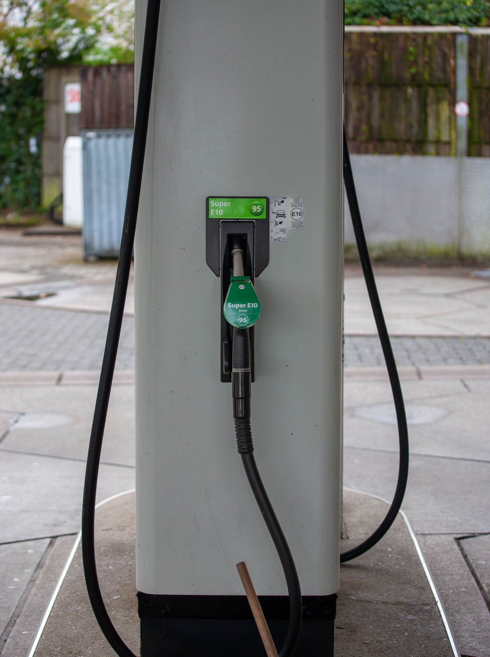 Electric vehicle charging station on a sidewalk, with a plugged-in cable and green charger indicator.