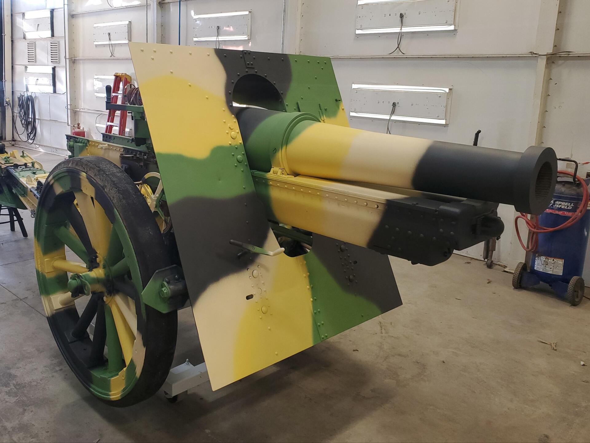 Camouflaged artillery cannon in a workshop.