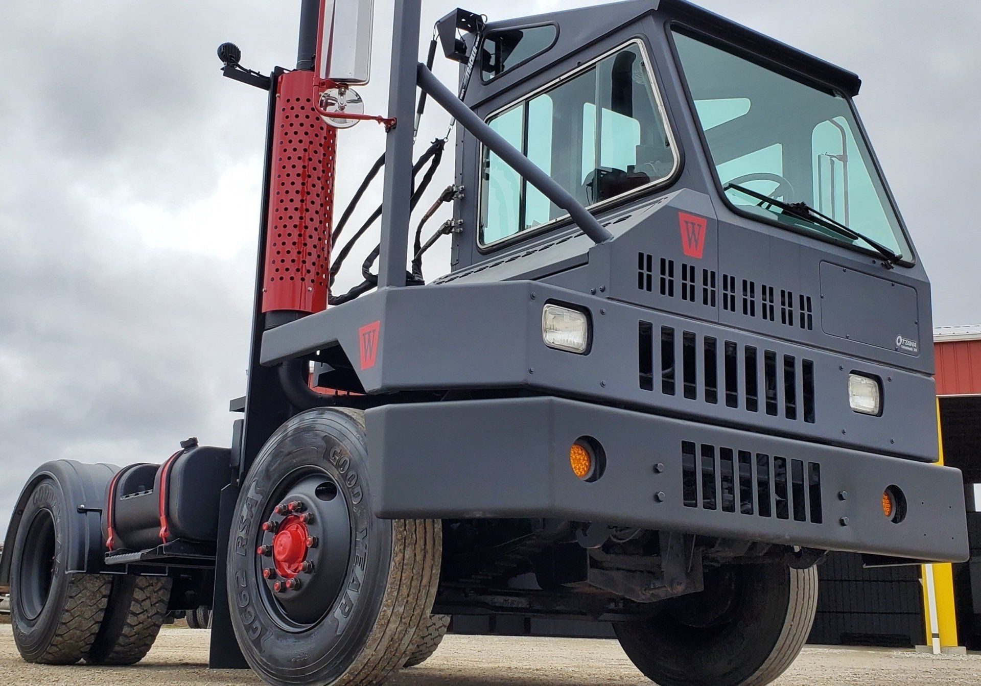 Dark gray yard truck with black and red accents, parked outside.