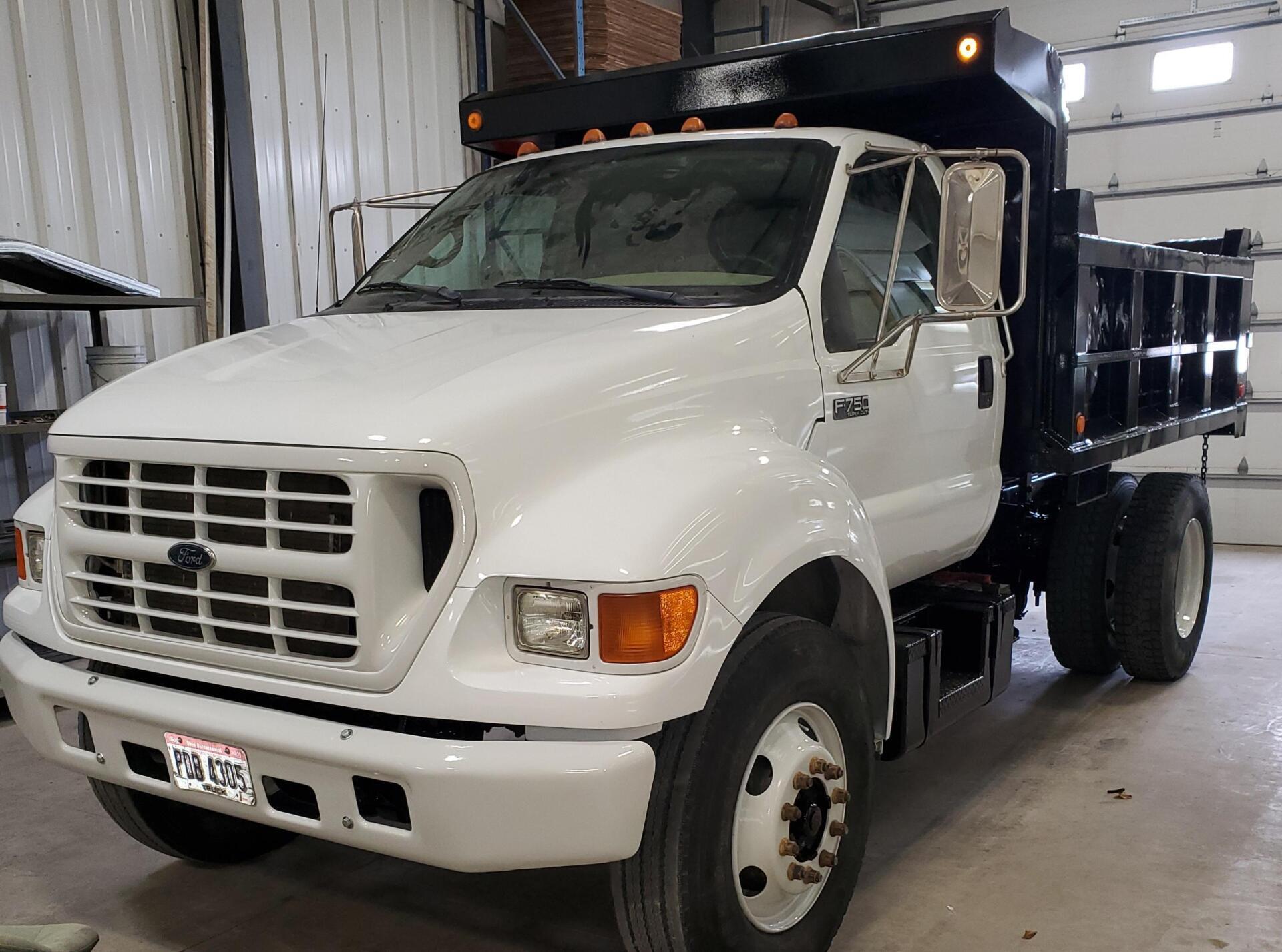 White and black dump truck parked inside a garage.