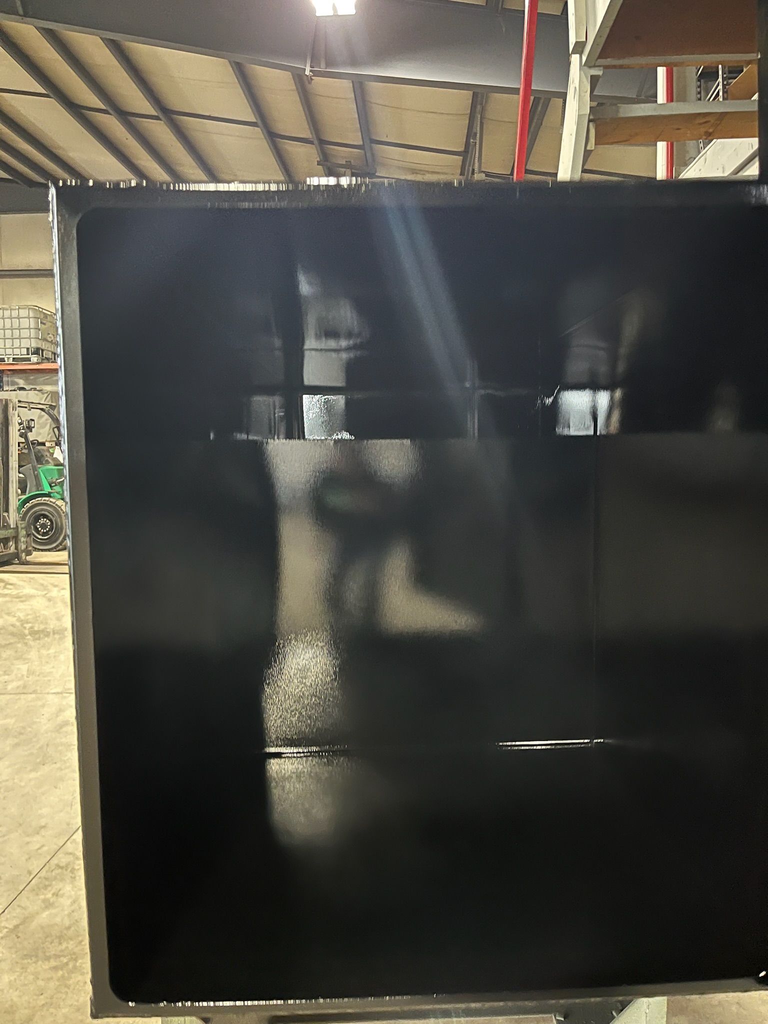 Black painted metal panel in a workshop setting.