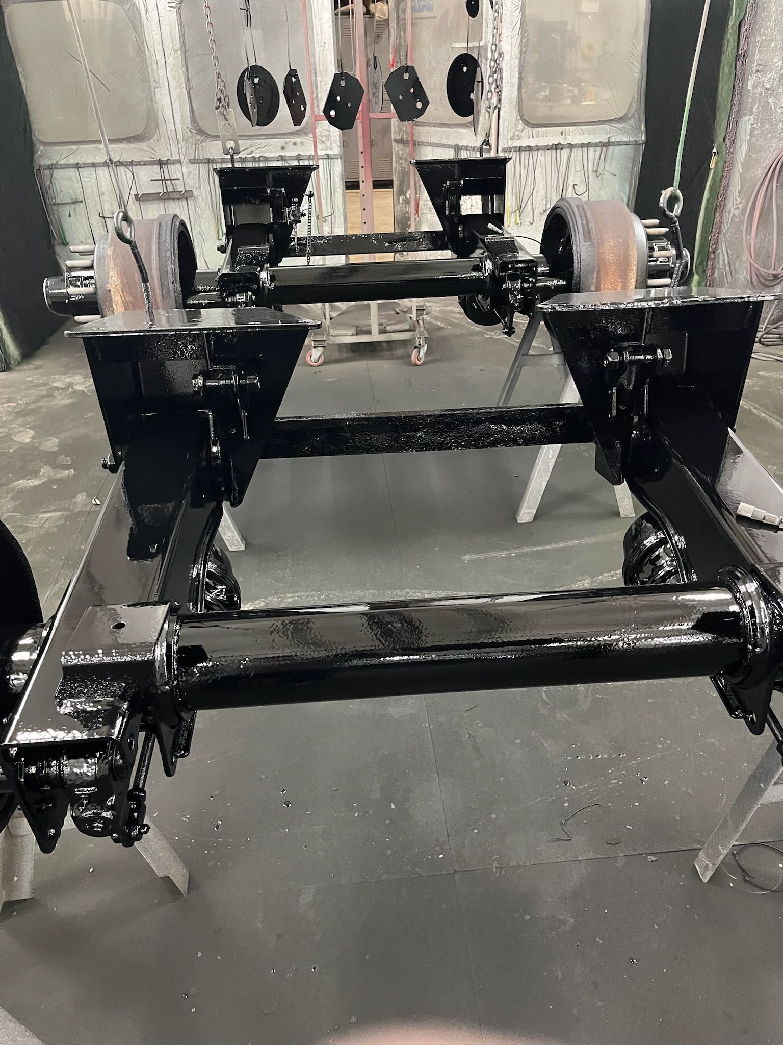 Black painted vehicle chassis on stands in a workshop.