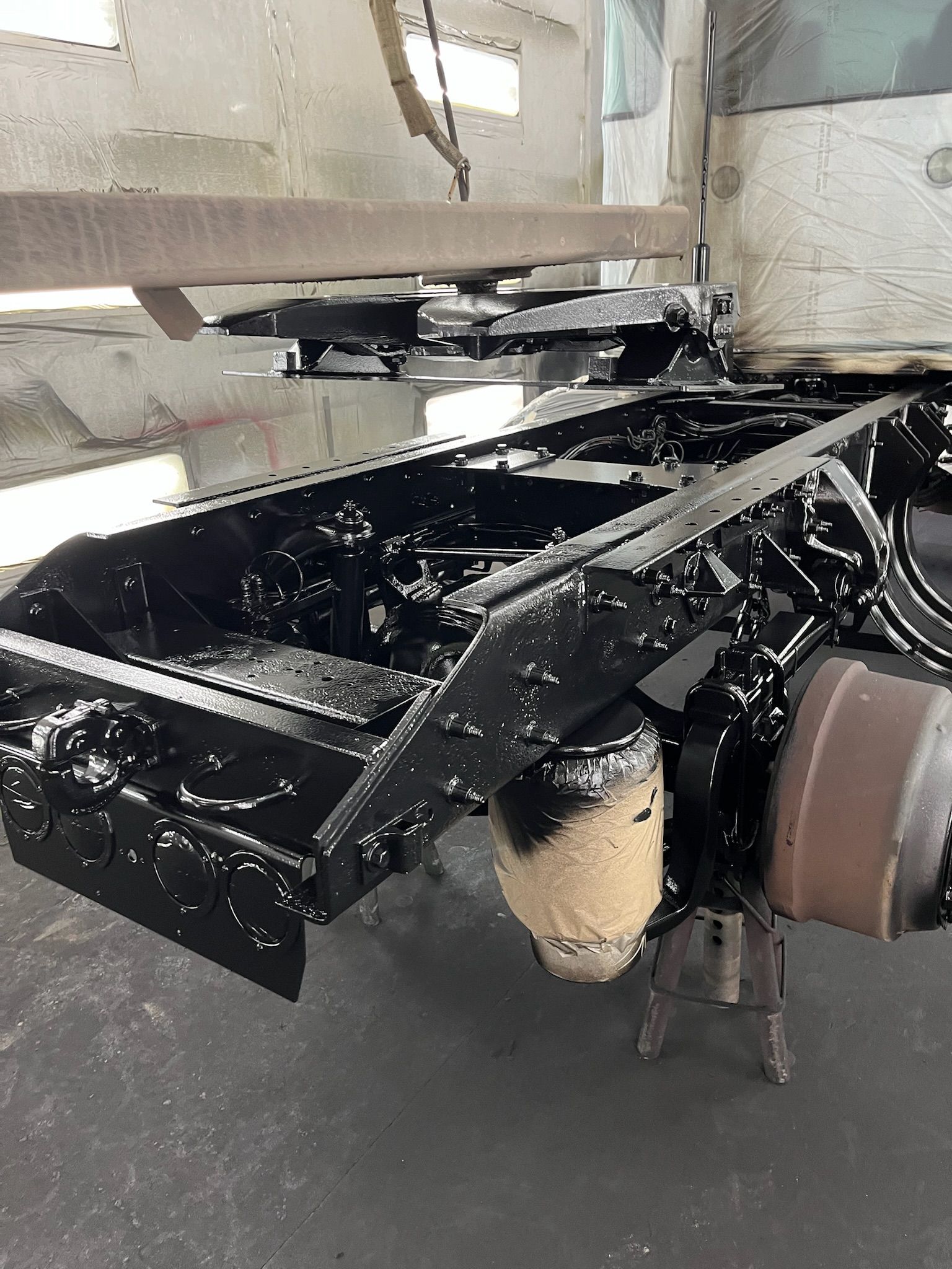 Black painted truck frame in a shop setting.