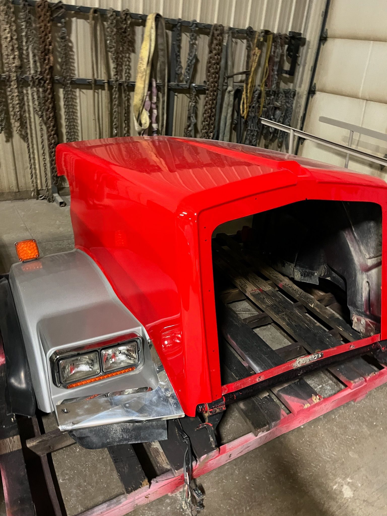Red truck cab with silver hood in a workshop.